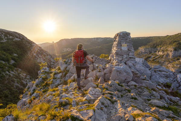 Hiker admires the sunset on Cippo Comici, Rosandra Valley, Trieste province, Friuli Venezia Giulia, Italy.