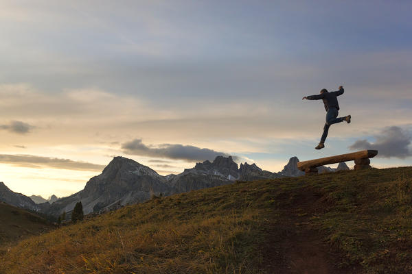 A hiker jumps in fornt of Lagazuoi, Dolomites, Cortina d'Ampezzo, Belluno province, Veneto, Italy