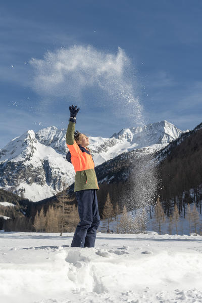 Rein in Taufers, Campo Tures / Sand in Tauers, Bolzano district, South Tyrol, Italy, Europe. Happy girl throwing snow in the air