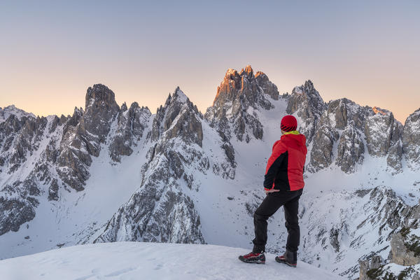 Mount Campedelle, Misurina, Auronzo di Cadore, province of Belluno, Veneto, Italy, Europe. Mountaineer admires the sunrise in the rocky peaks of the Cadini mountains