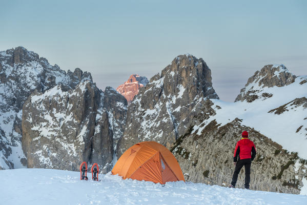 Mount Campedelle, Misurina, Auronzo di Cadore, province of Belluno, Veneto, Italy, Europe. A mountaineer admires the sunrise in the Cadini di Misurina mountains, the Punta Sorapiss is illuminated by the first sunlight