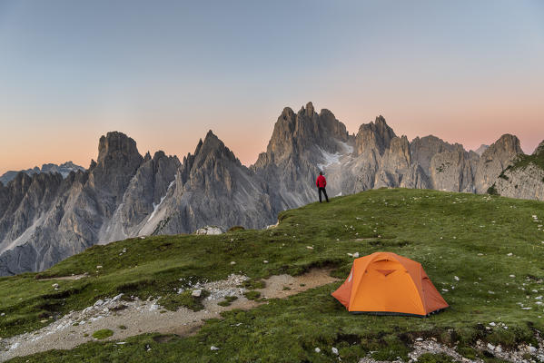 Mount Campedelle, Misurina, Auronzo di Cadore, province of Belluno, Veneto, Italy, Europe. A mountaineer admires the sunrise in the Cadini di Misurina mountains