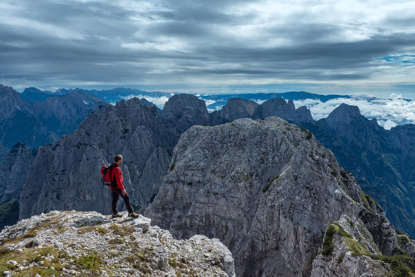 Pizzon, Monti del Sole, Dolomites, Veneto, Italy. Mountaineer on the summit of Pizzon. In the background the Monti del Sole