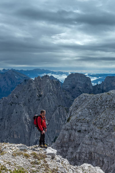 Pizzon, Monti del Sole, Dolomites, Veneto, Italy. Mountaineer on the summit of Pizzon. In the background the Monti del Sole