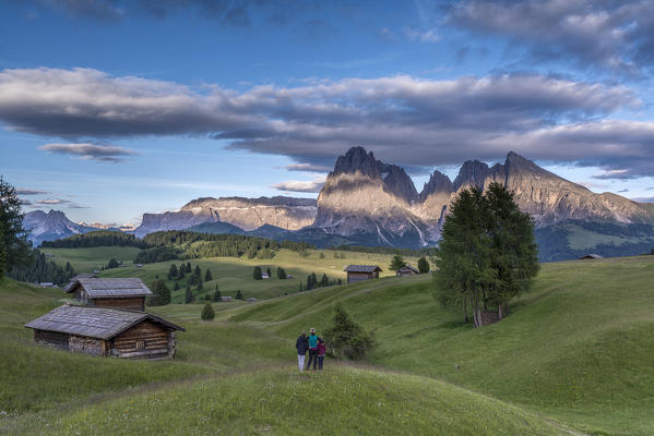 Alpe di Siusi/Seiser Alm, Dolomites, South Tyrol, Italy. Mountaineers on the Alpe di Siusi admire the alpenglow. In the background the Sella, Sassolungo/Langkofel and Sassopiatto/Plattkofel