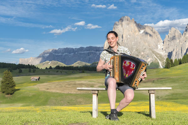 Alpe di Siusi/Seiser Alm, Dolomites, South Tyrol, Italy. Young woman playing with the accordion at the Alpe di Siusi