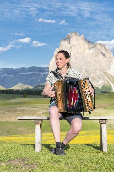 Alpe di Siusi/Seiser Alm, Dolomites, South Tyrol, Italy. Young woman playing with the accordion at the Alpe di Siusi