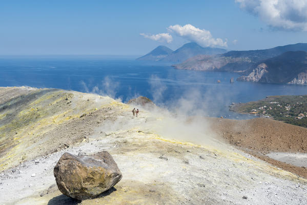 Volcano, Messina district, Sicily, Italy, Europe. Sulfur fumaroles on the crater rim of Vulcano. In the background the islands of Lipari and Salina