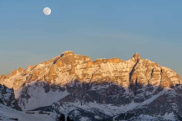 Gardena Pass, Alta Badia, province of Bolzano, South Tyrol, Italy, Europe. While the rocks of the Lavarella and Conturines glow in the sunset, the full moon rises