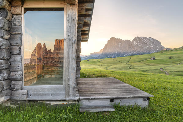 Alpe di Siusi/Seiser Alm, Dolomites, South Tyrol, Italy. Sunrise on the Alpe di Siusi/Seiser Alm. The peaks of the Sciliar are reflected in a glass pane