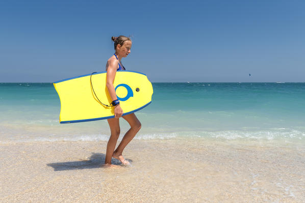 Sirolo, province of Ancona, Marche, Italy, Europe. A girl with a surfboard on the San Michele beach