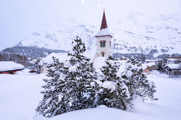 Snowy landscape and the typical church Maloja Canton of Graubünden Engadine Switzerland Europe