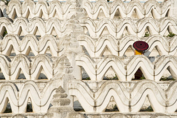 Mingun, Sagaing region, Myanmar (Burma). Woman with red umbrella in the middle of the white terraces of the Hsinbyume white pagoda.