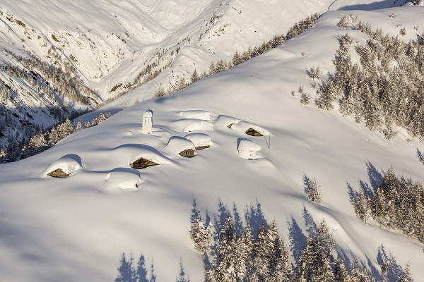 Italy, Italian Alps, Lombardy, The huts and the bell tower of Alpe Cima sorrounded by metres of snow