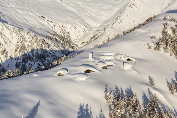 Italy, Italian Alps, Lombardy, The huts and the bell tower of Alpe Cima sorrounded by metres of snow