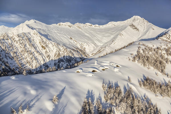 Italy, Italian Alps, Lombardy, The huts and the bell tower of Alpe Cima sorrounded by metres of snow