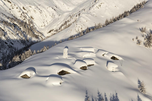 Italy, Italian Alps, Lombardy, The huts and the bell tower of Alpe Cima sorrounded by metres of snow