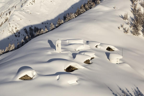 Italy, Italian Alps, Lombardy, The huts and the bell tower of Alpe Cima sorrounded by metres of snow