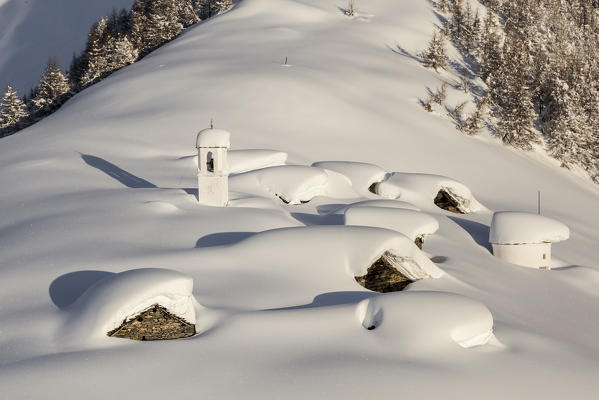 Italy, Italian Alps, Lombardy, The huts and the bell tower of Alpe Cima sorrounded by metres of snow