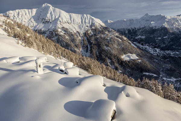 Italy, Italian Alps, Lombardy, The huts and the bell tower of Alpe Cima sorrounded by metres of snow