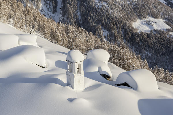 Italy, Italian Alps, Lombardy, The huts and the bell tower of Alpe Cima sorrounded by metres of snow