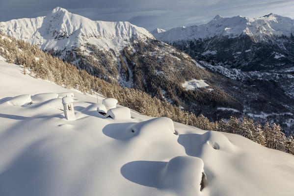 Italy, Italian Alps, Lombardy, The huts and the bell tower of Alpe Cima sorrounded by metres of snow