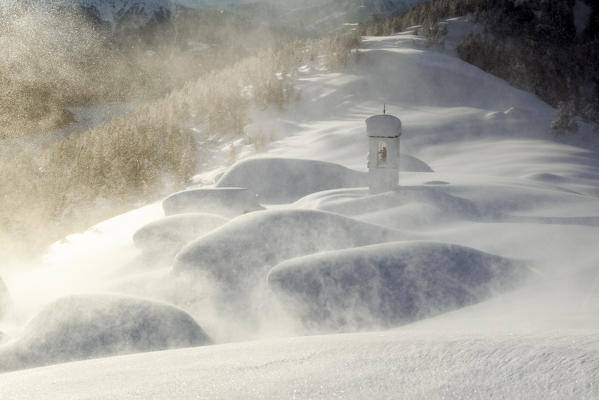 Italy, Italian Alps, Lombardy, The huts and the bell tower of Alpe Cima sorrounded by metres of snow