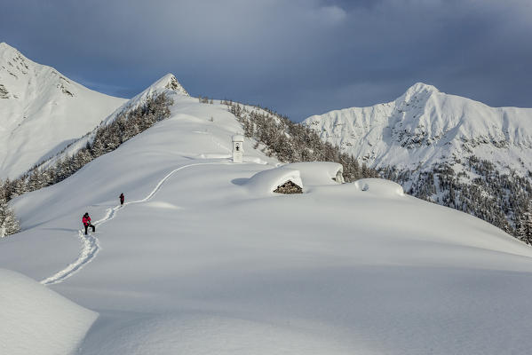 Italy, Italian Alps, Lombardy, The huts and the bell tower of Alpe Cima sorrounded by metres of snow