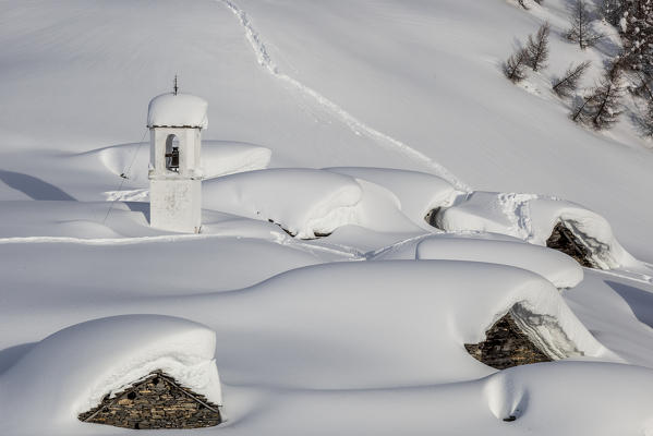 Italy, Italian Alps, Lombardy, The huts and the bell tower of Alpe Cima sorrounded by metres of snow