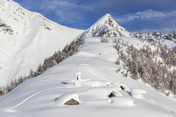 Italy, Italian Alps, Lombardy, The huts and the bell tower of Alpe Cima sorrounded by metres of snow