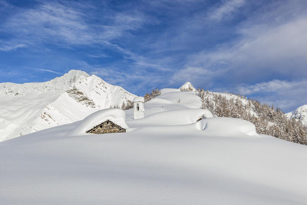 Italy, Italian Alps, Lombardy, The huts and the bell tower of Alpe Cima sorrounded by metres of snow