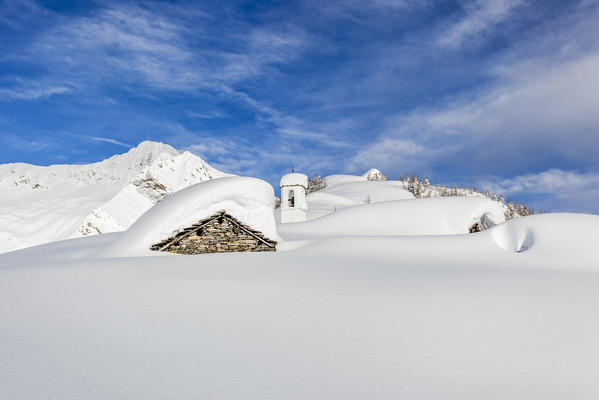 Italy, Italian Alps, Lombardy, The huts and the bell tower of Alpe Cima sorrounded by metres of snow