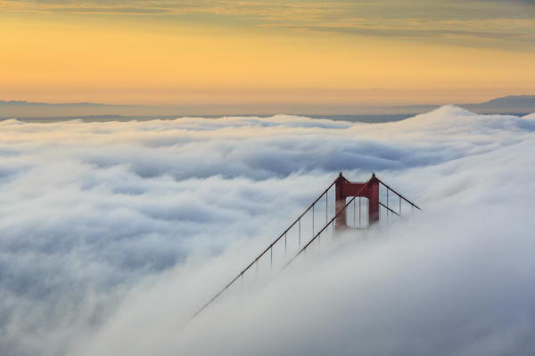 Golden Gate Bridge emerging from the morning fog at sunrise. San Francisco, Marin County, California, USA.