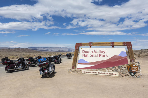 Death Valley National Park, Inyo County, California, USA. Park entrance signpost and motorbikes.