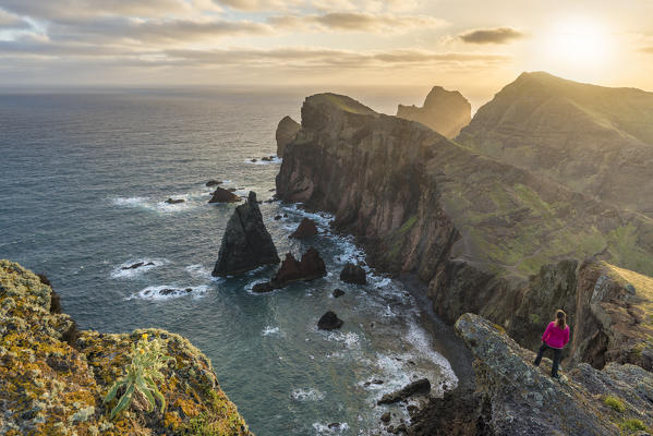 Woman admiring the view of Point of St Lawrence and Furado Point at dawn. Canical, Machico district, Madeira region, Portugal.