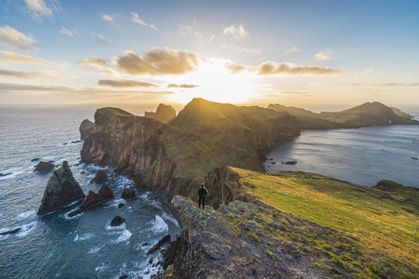 Woman admiring the view of point of St Lawrence and Furado Point at dawn. Canical, Machico district, Madeira region, Portugal.