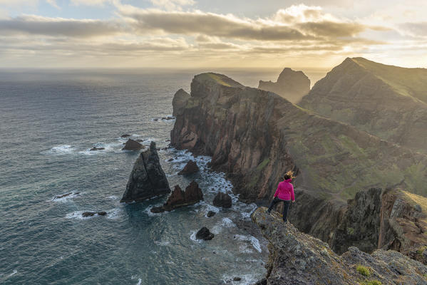 Woman admiring the view of Point of St Lawrence and Furado Point on a windy day. Canical, Machico district, Madeira region, Portugal.