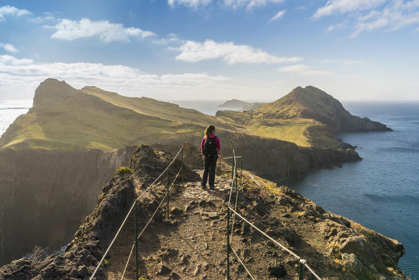 Woman on the trail admiring the view of Point of St Lawrence and Furado Point. Canical, Machico district, Madeira region, Portugal. (MR)