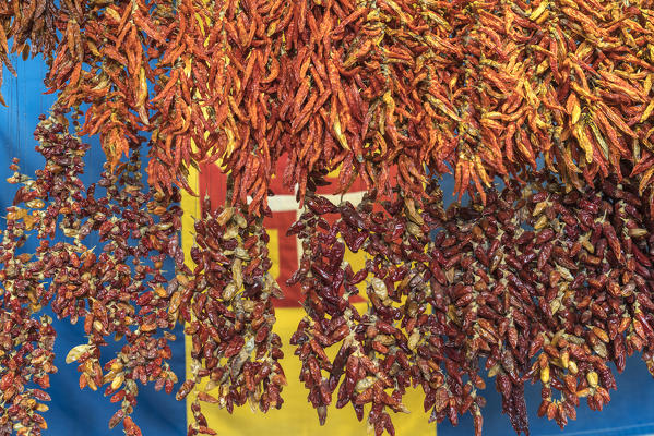 Dried chili peppers and the flag of Madeira in the background at Mercado dos Lavradores - Farmers' Market. Funchal, Madeira region, Portugal.