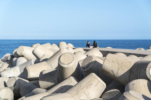 Couple sitting on the dock in Funchal, Madeira region, Portugal.