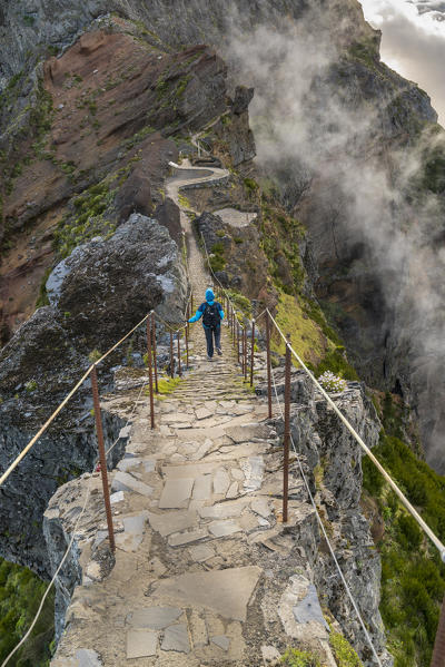 Hiker descending the steps on Vereda do Areeiro, the trail that links Pico Ruivo to Pico do Arieiro, Funchal, Madeira region, Portugal.