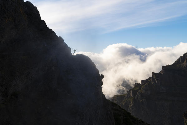 Hiker waving on Vereda do Areeiro, the trail that links Pico Ruivo to Pico do Arieiro, Funchal, Madeira region, Portugal.