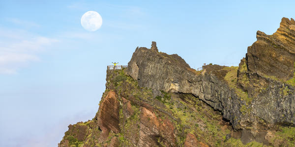 Full moon above Nino da Manta lookout and man waving from the platform. Pico do Arieiro, Funchal, Madeira region, Portugal.