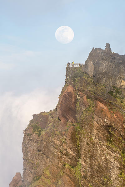 Full moon above Nino da Manta lookout and two people on the platform. Pico do Arieiro, Funchal, Madeira region, Portugal.