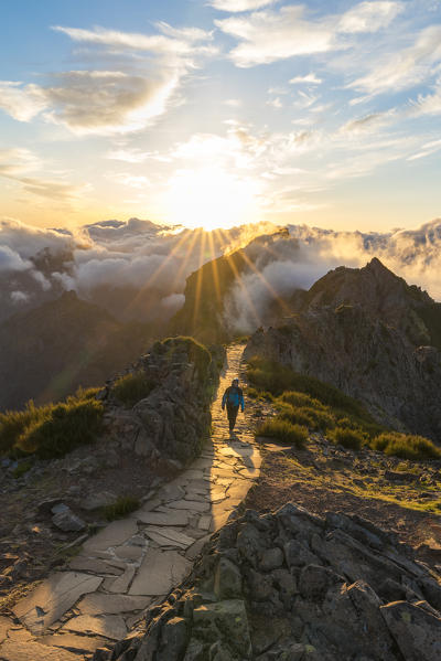 Hiker walking at sunset on Vereda do Areeiro, the trail that links Pico Ruivo to Pico do Arieiro, Funchal, Madeira region, Portugal. (MR)