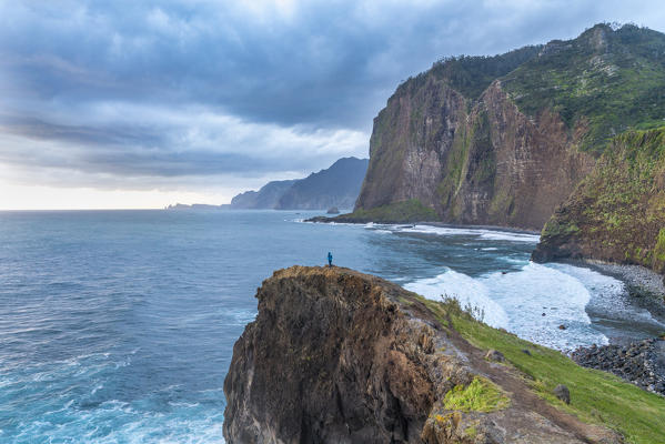 Person on a cliff watching the sunrise. Faial, Santana municipality, Madeira region, Portugal.