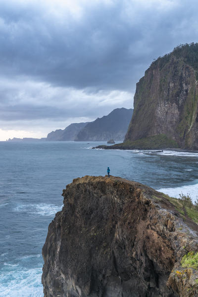 Person on a cliff watching the sunrise. Faial, Santana municipality, Madeira region, Portugal.