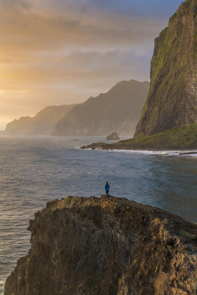 Person on a cliff watching the sunrise. Faial, Santana municipality, Madeira region, Portugal.