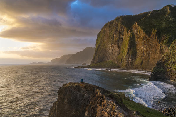 Person on a cliff watching the sunrise. Faial, Santana municipality, Madeira region, Portugal.