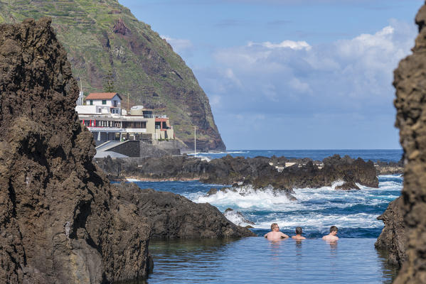 Three men bathing in the natural pools of Porto Moniz, Madeira region, Portugal.